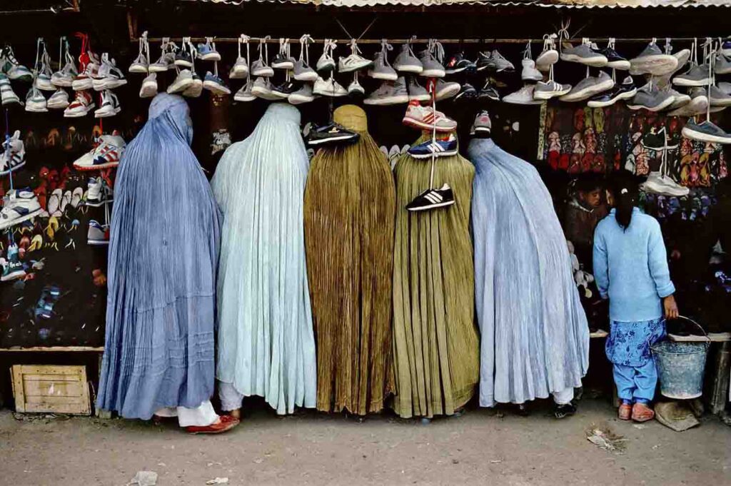 MCCURRY THE PURSUIT OF COLOR. Afghan Women at Shoe Store. Kabul, Afghanistan, 1992.